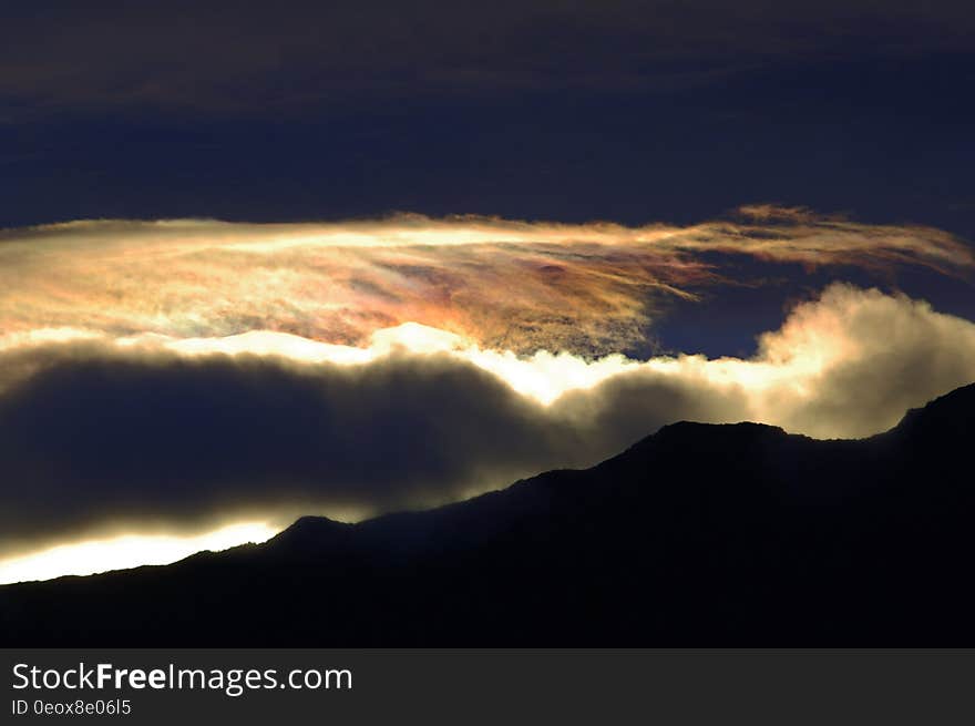 The sunset over a mountain range with light shining through the clouds. The sunset over a mountain range with light shining through the clouds.
