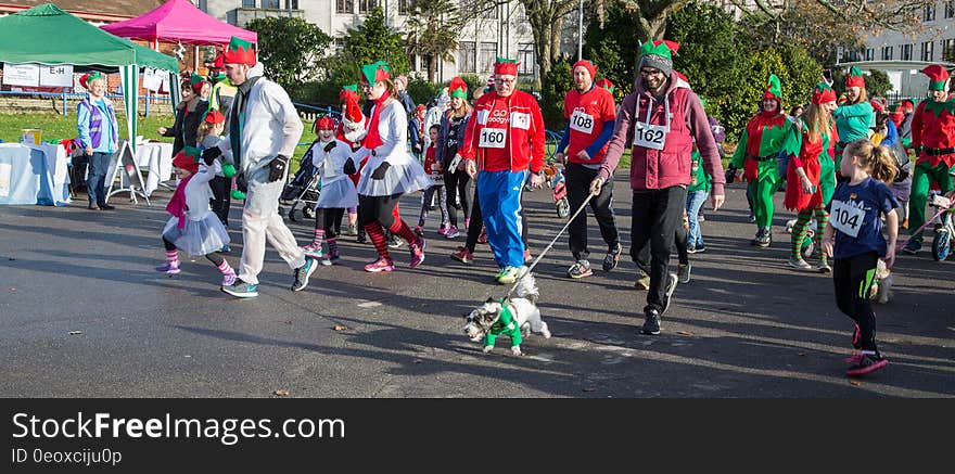 Parade of people dressed as Christmas elves walking on sunny city street. Parade of people dressed as Christmas elves walking on sunny city street.