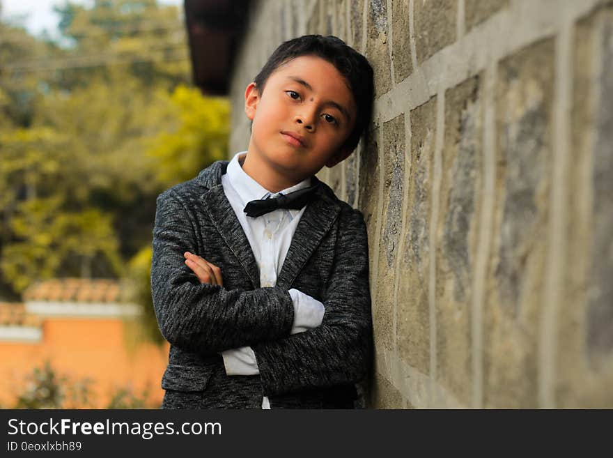 An elegantly dressed boy leaning against a wall. An elegantly dressed boy leaning against a wall.