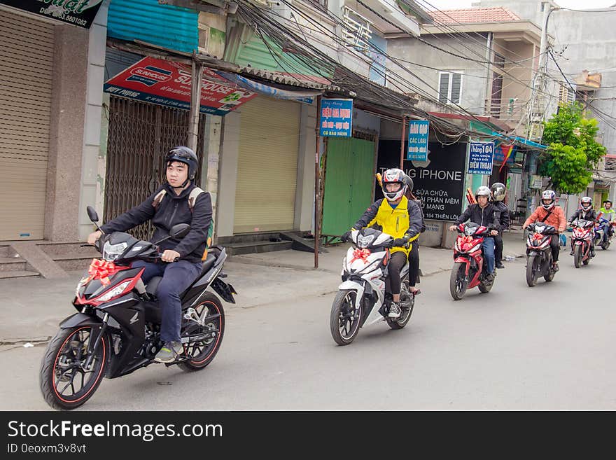 Motorcyclists riding motorbikes one behind another along a street. Motorcyclists riding motorbikes one behind another along a street.