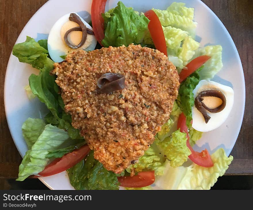 Breaded and fried meat on lettuce salad with tomato slices and hard boiled eggs. Breaded and fried meat on lettuce salad with tomato slices and hard boiled eggs.