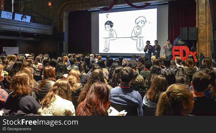 Speakers onstage in crowded hall during 2016 TEDx conference.