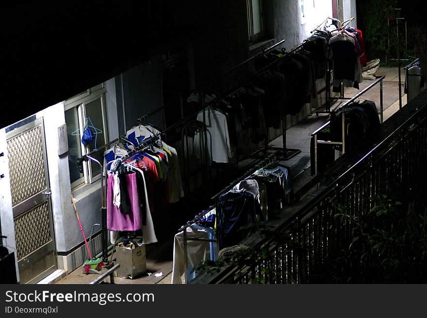 Racks of clothes outdoors on walkway at night.