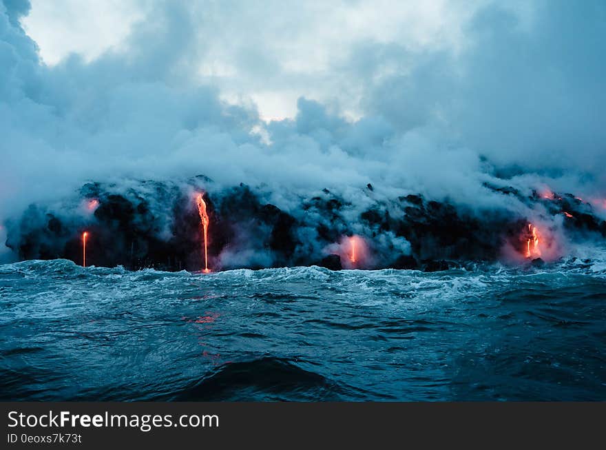 Lava streams flowing into water with steam and waves. Lava streams flowing into water with steam and waves.