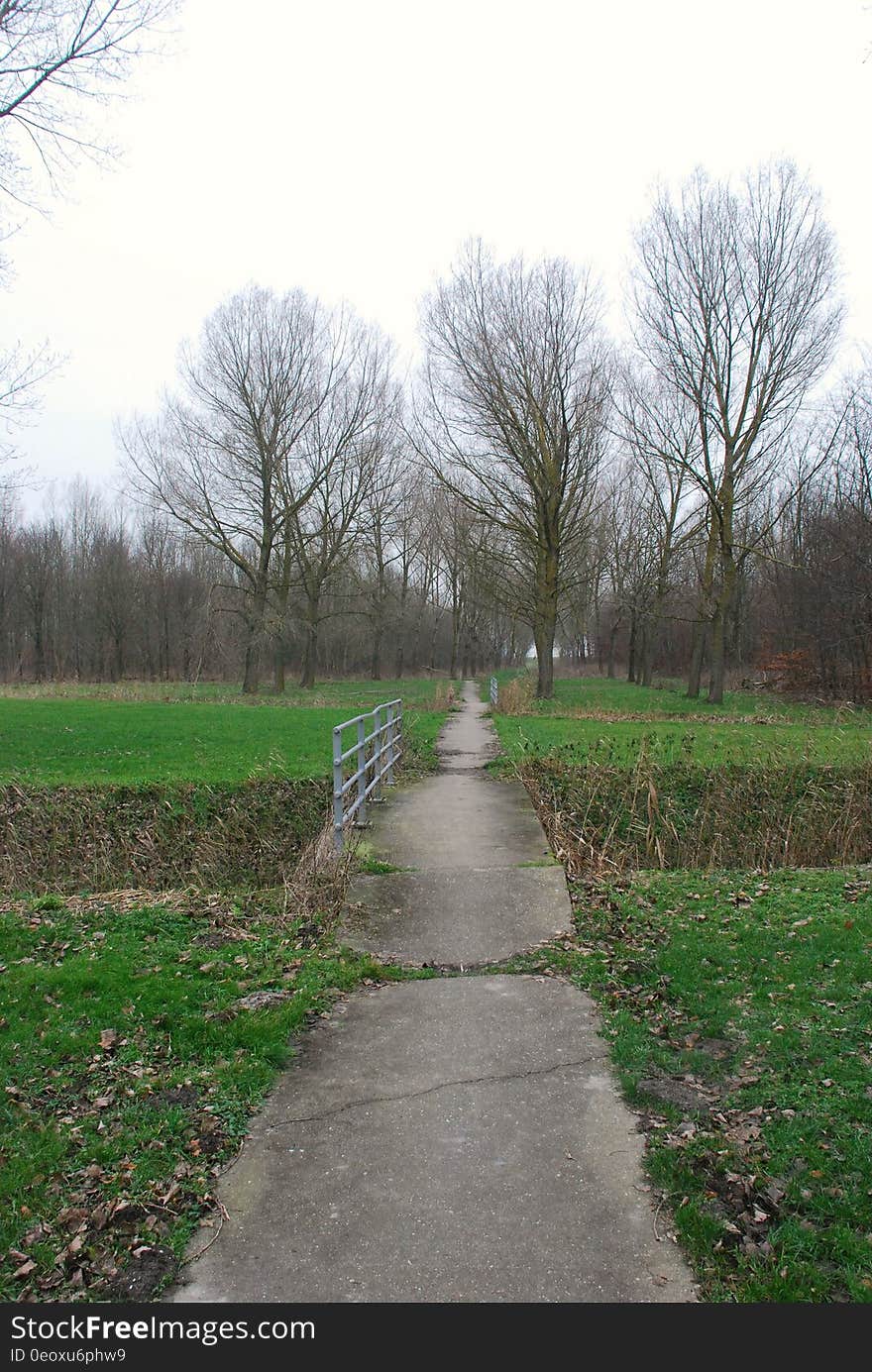 Concrete walkway and bridge through green fields in country on sunny day. Concrete walkway and bridge through green fields in country on sunny day.