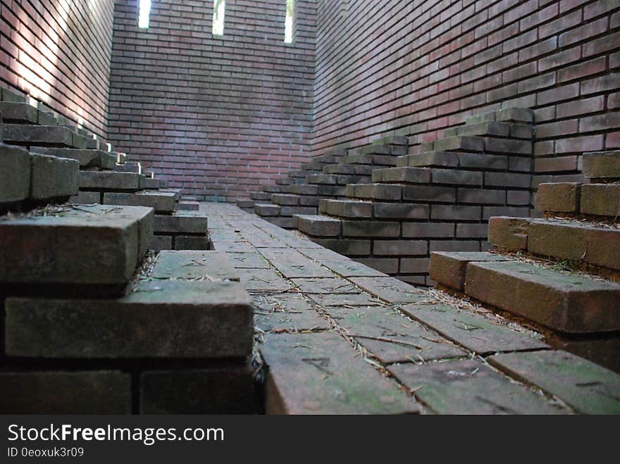 Cobblestone walk outside brick building in shadows.