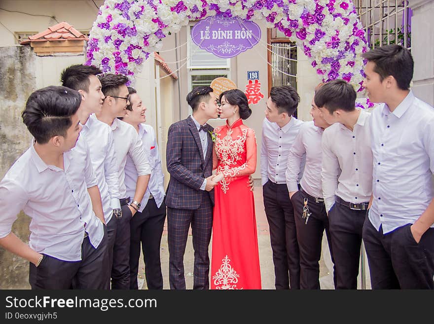 Asian wedding kissing under banner with guests watching. Asian wedding kissing under banner with guests watching.