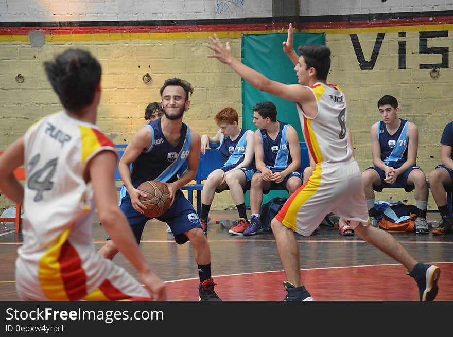 Action shot of young men playing basketball on an indoor court.