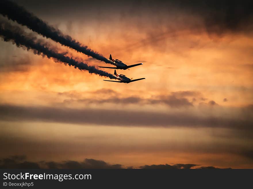 Airplanes flying in formation against setting sun with black smoke trails. Airplanes flying in formation against setting sun with black smoke trails.