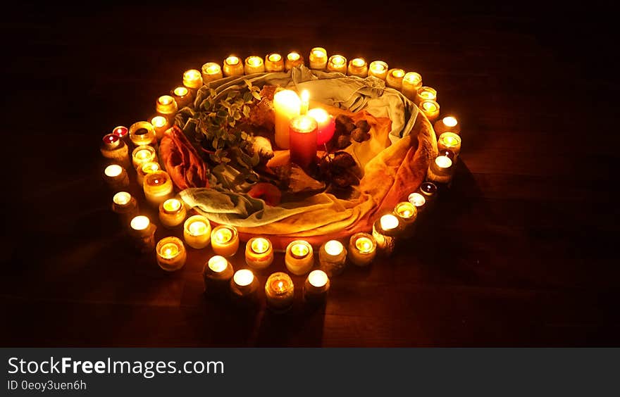 Ring of illuminated candles in display with colorful cloth on black. Ring of illuminated candles in display with colorful cloth on black.