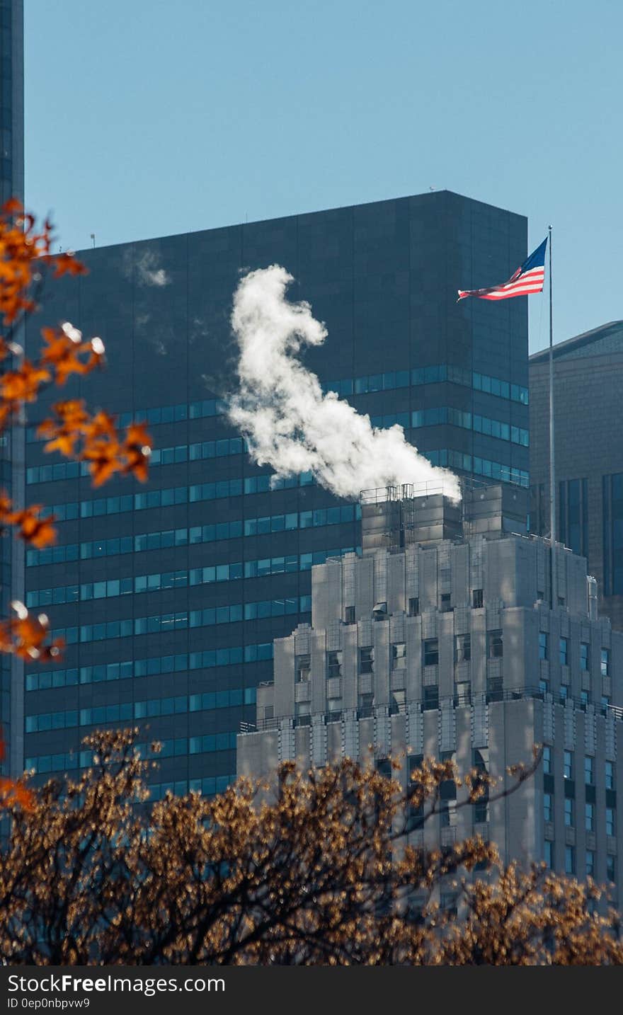 Steam coming from rooftop of modern building in city skyline with American flag. Steam coming from rooftop of modern building in city skyline with American flag.