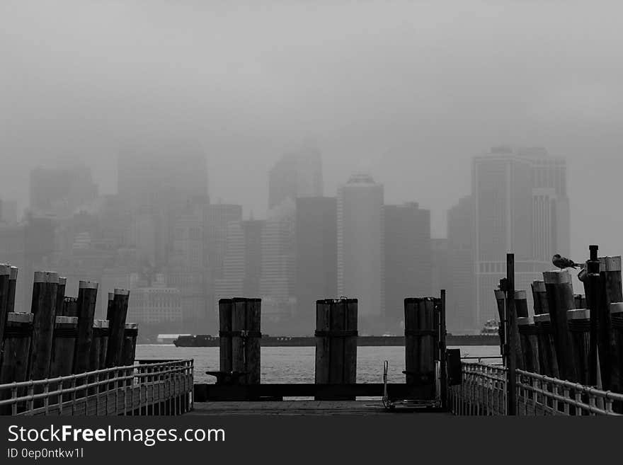 Wharf along waterfront with Manhattan, New York skyline in fog.