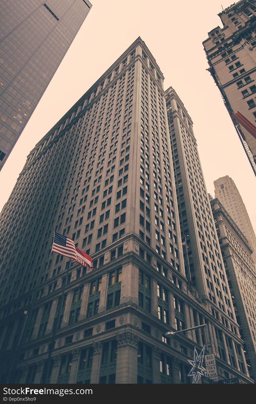 Low angle looking to the top of skyscrapers in a city with American flag, sepia tone. Low angle looking to the top of skyscrapers in a city with American flag, sepia tone.