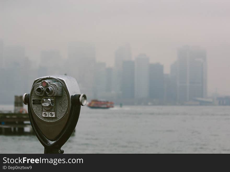 Public binocular style telescope looking over river with New York city skyline in background, USA. Public binocular style telescope looking over river with New York city skyline in background, USA.