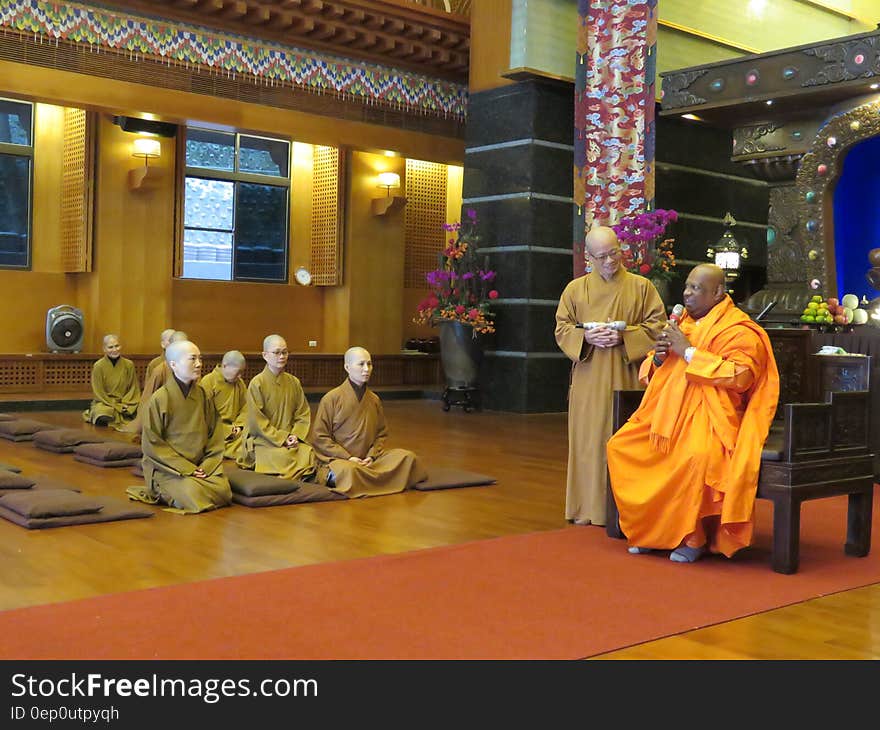 Monks in robes seated inside modern temple. Monks in robes seated inside modern temple.