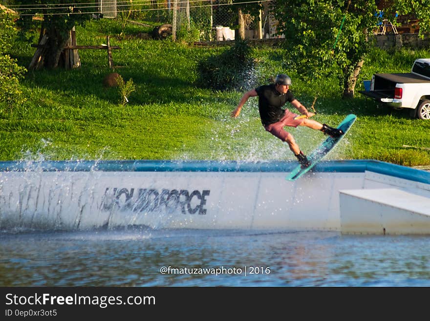 Man riding water board in cement pool on sunny day. Man riding water board in cement pool on sunny day.