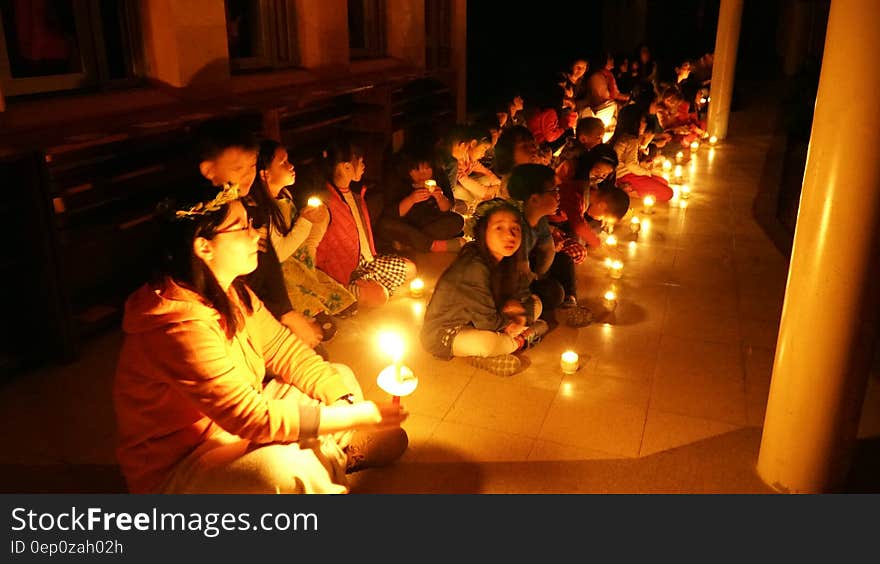 Children sitting with candles inside room. Children sitting with candles inside room.