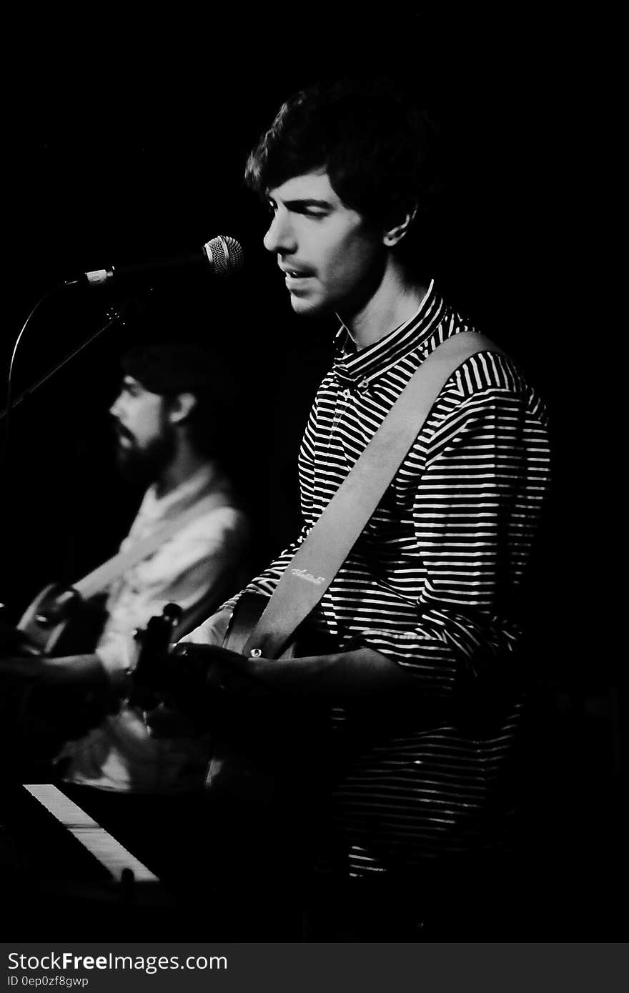 Men playing guitars and singing onstage during concert in black and white. Men playing guitars and singing onstage during concert in black and white.