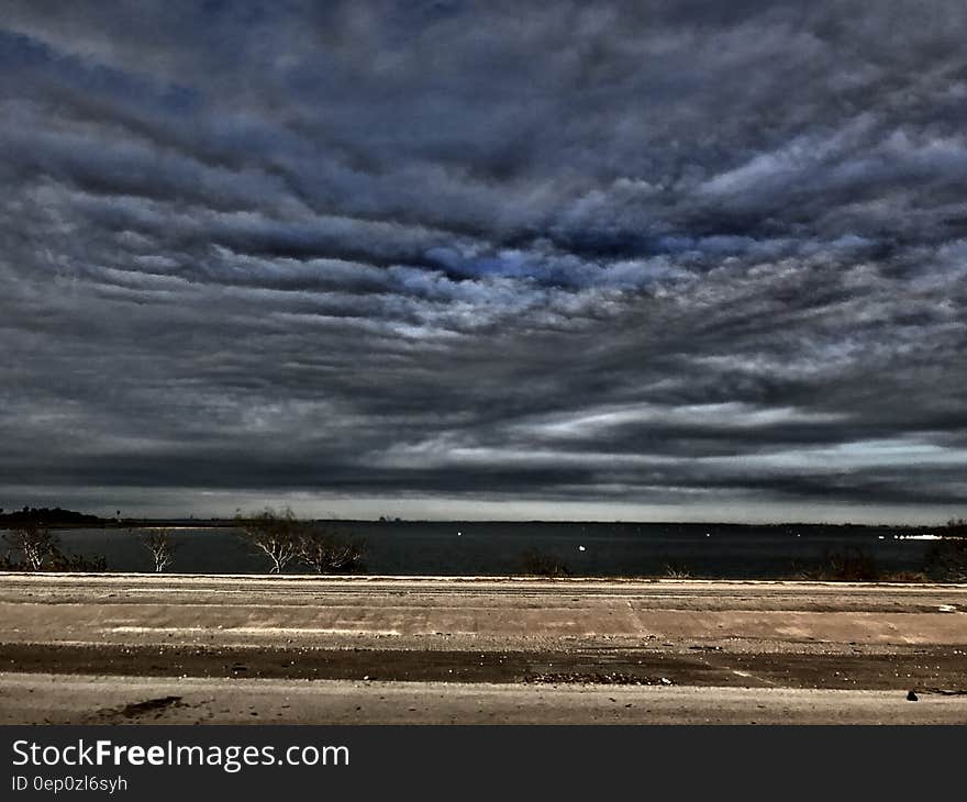 Dramatic clouds in sky over rural country field in daytime. Dramatic clouds in sky over rural country field in daytime.