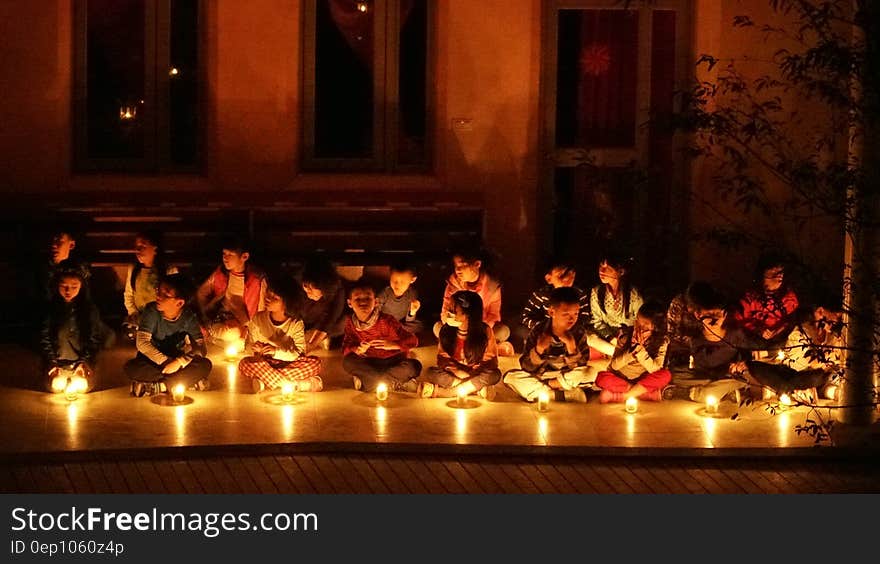 Children seated on floor indoors with candles during candlelight ceremony. Children seated on floor indoors with candles during candlelight ceremony.