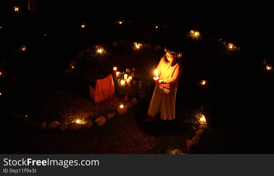 Girl holding candles outdoors in garden illuminated with lanterns. Girl holding candles outdoors in garden illuminated with lanterns.