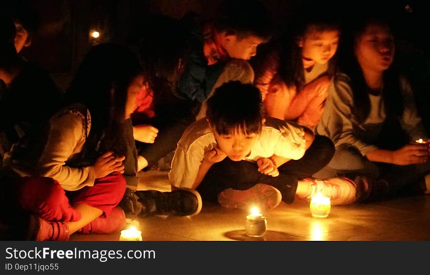 Children sitting on floor looking at candles burning. Children sitting on floor looking at candles burning.