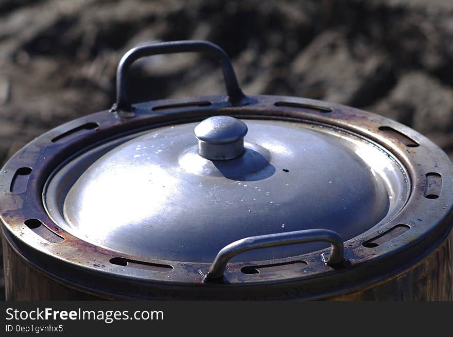 Close up of metal pot with lid outdoors on sunny day.