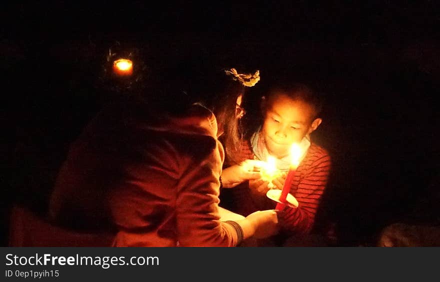 Boy and girl lighting candles during nighttime ceremony. Boy and girl lighting candles during nighttime ceremony.