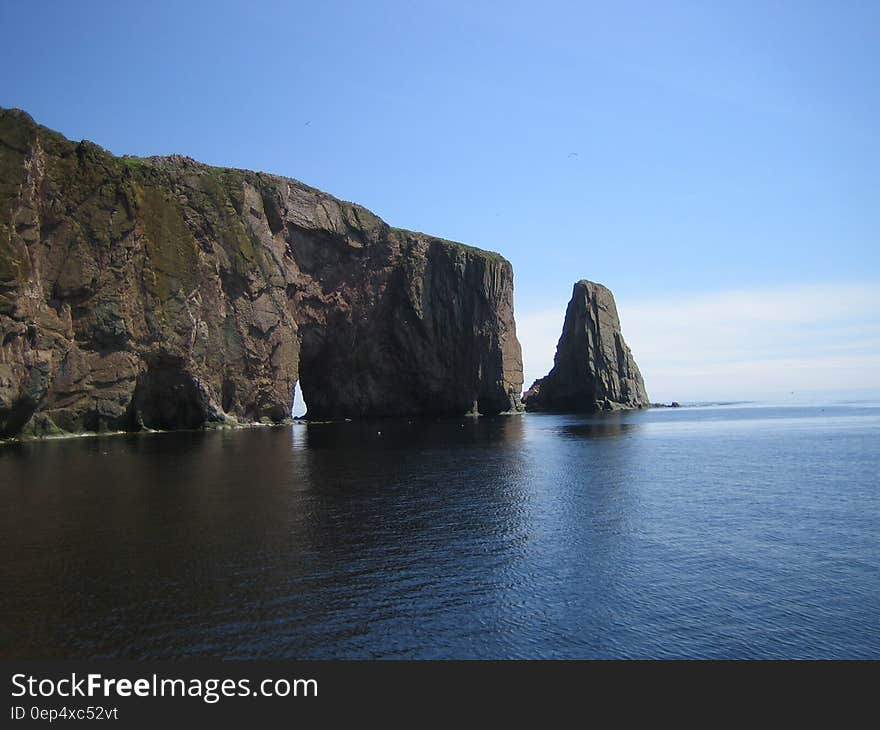 Grey Cliff on Blue Calm Sea during Daytime