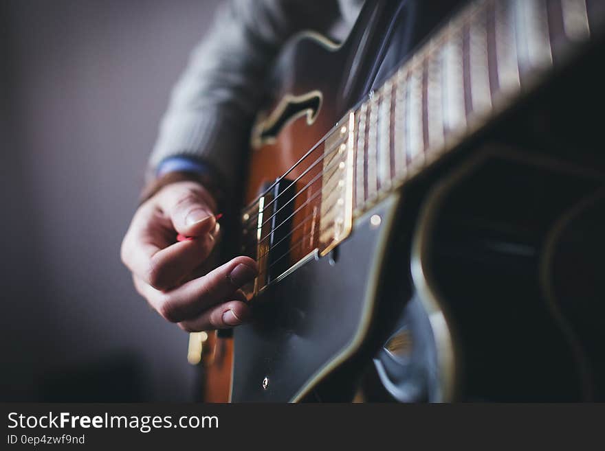 Close up of man's hands strumming electric guitar with pick. Close up of man's hands strumming electric guitar with pick.