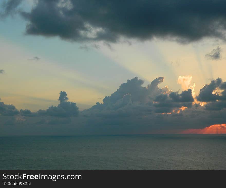 Clouds in skies over water with setting sun and blue skies. Clouds in skies over water with setting sun and blue skies.