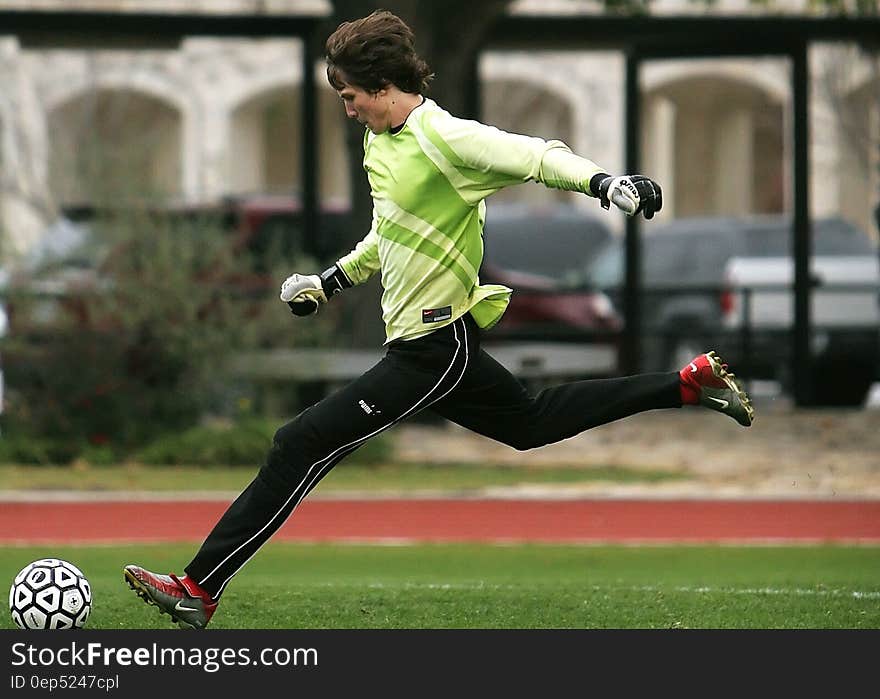 Man in Black Pants Playing Soccer during Daytime