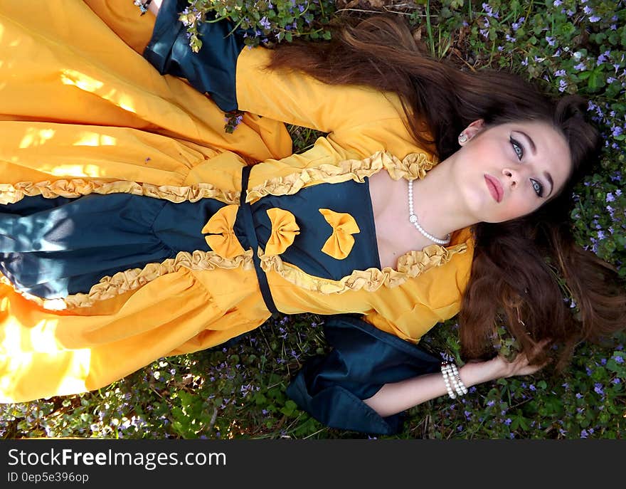 Woman in Yellow and Blue Dress Lying on a Grass Field