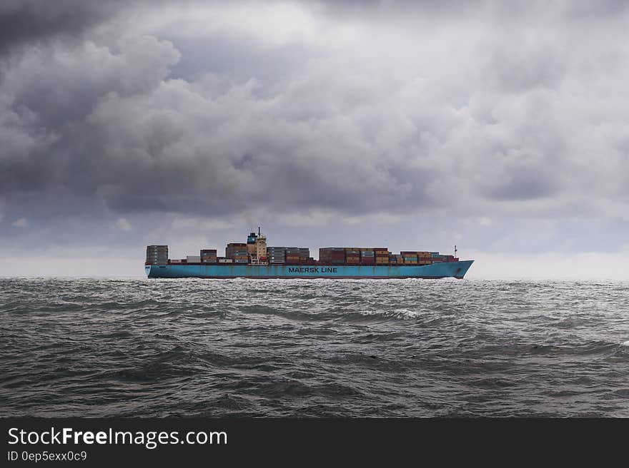 Cargo ship navigating grey choppy waters with stormy skies. Cargo ship navigating grey choppy waters with stormy skies.