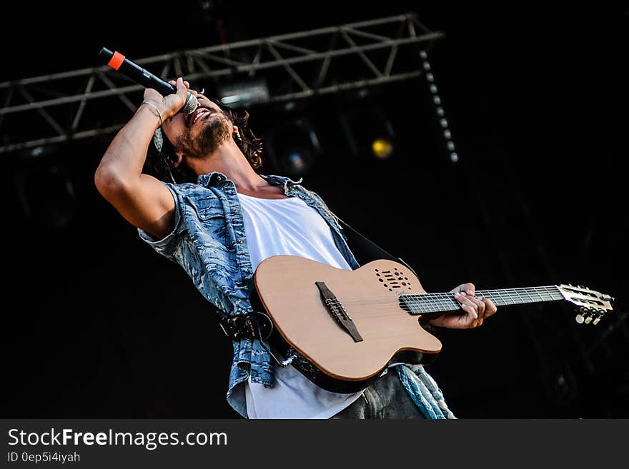 Man Using Brown and Black Electric Guitar While Singing