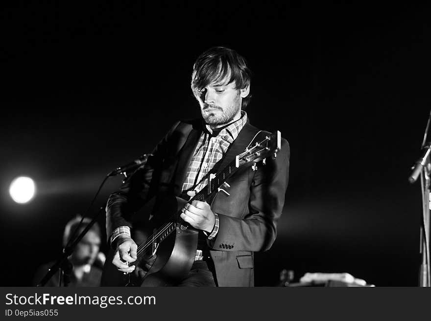 Puggy Ronquieres playing guitar performing onstage in concert in black and white. Puggy Ronquieres playing guitar performing onstage in concert in black and white.