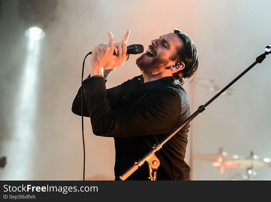 Man Wearing Black Collared Long Sleeve Shirt Holding Microphone