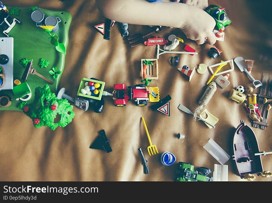 Green Rectangular Toy, Gray Boat Toy, Gray Shovel Toy, and Green Car Toy on Top of Brown Leather Surface