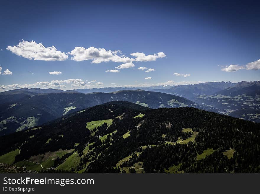 Aerial view over rolling green hill landscape with blue skies on sunny day. Aerial view over rolling green hill landscape with blue skies on sunny day.