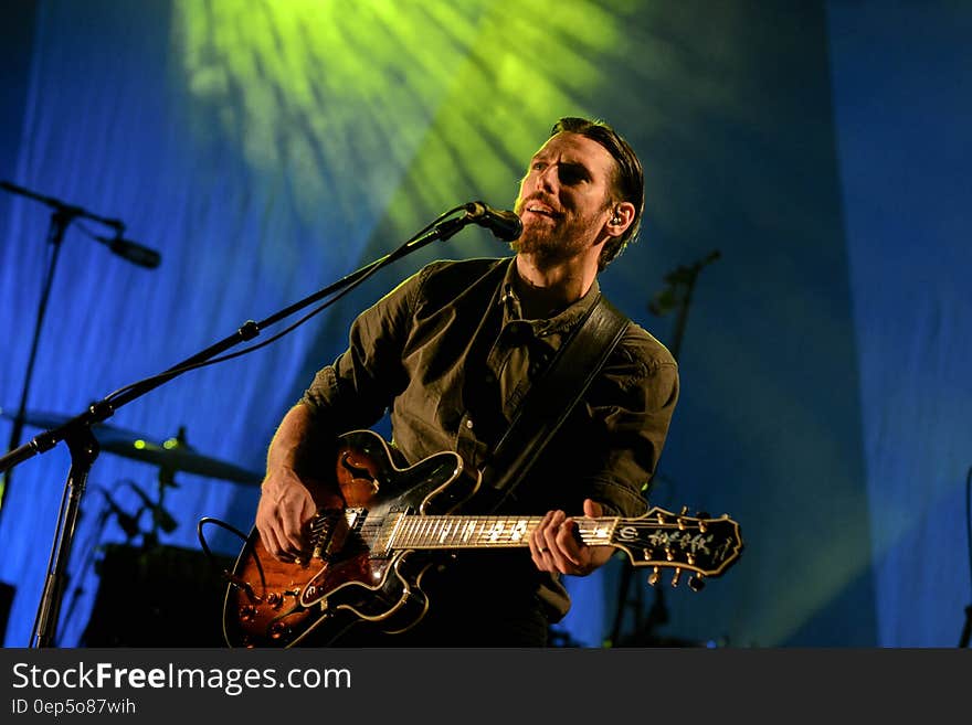 Man Playing Red and Black Electric Guitar on Stage