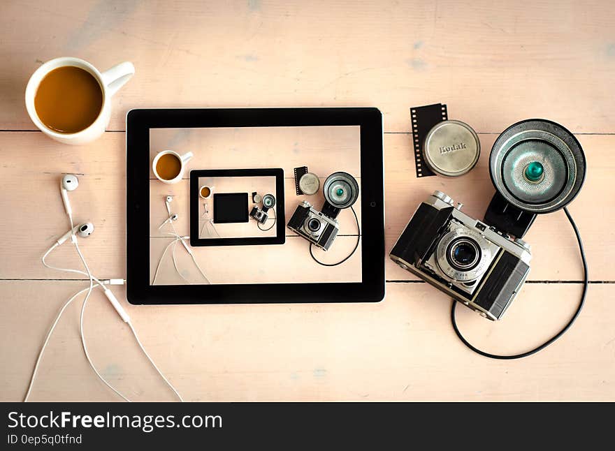 Still life of vintage film camera and tablet on wooden desktop with cup of coffee. Still life of vintage film camera and tablet on wooden desktop with cup of coffee.