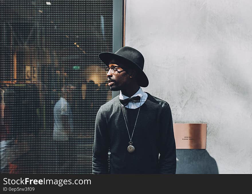 Man Wearing Black Hat a Bow and a Sweat Shirt on a Backstage