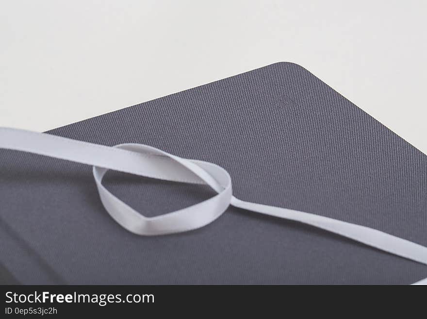 White Ribbon Formed Heart on Brown Rectangular Mat