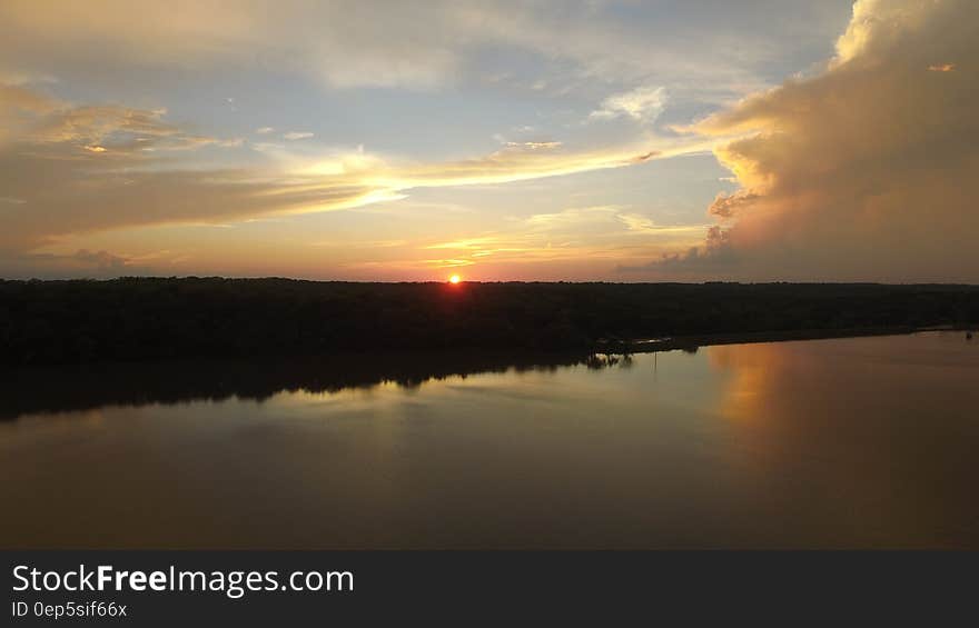 Sun setting behind the horizon by a lake. Sun setting behind the horizon by a lake.