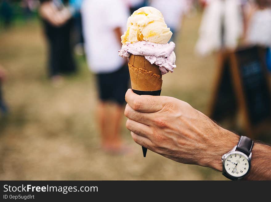 Person Holding Yellow and Purple Ice Cream