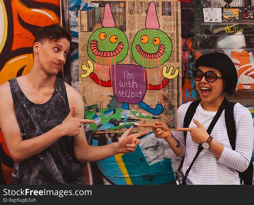 Man on Black Tank Top Pointing at Woman on White Long Sleeve Top