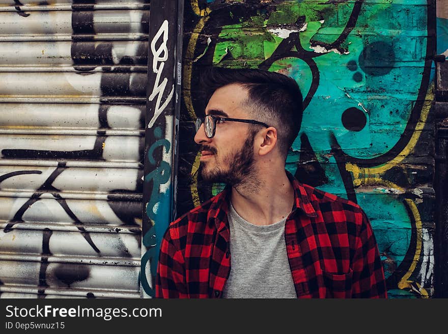 Man Wearing Black Framed Eyeglasses Standing Beside Blue and Black Wall