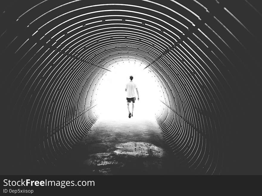 Grayscale Photo of Man Walking in Hole