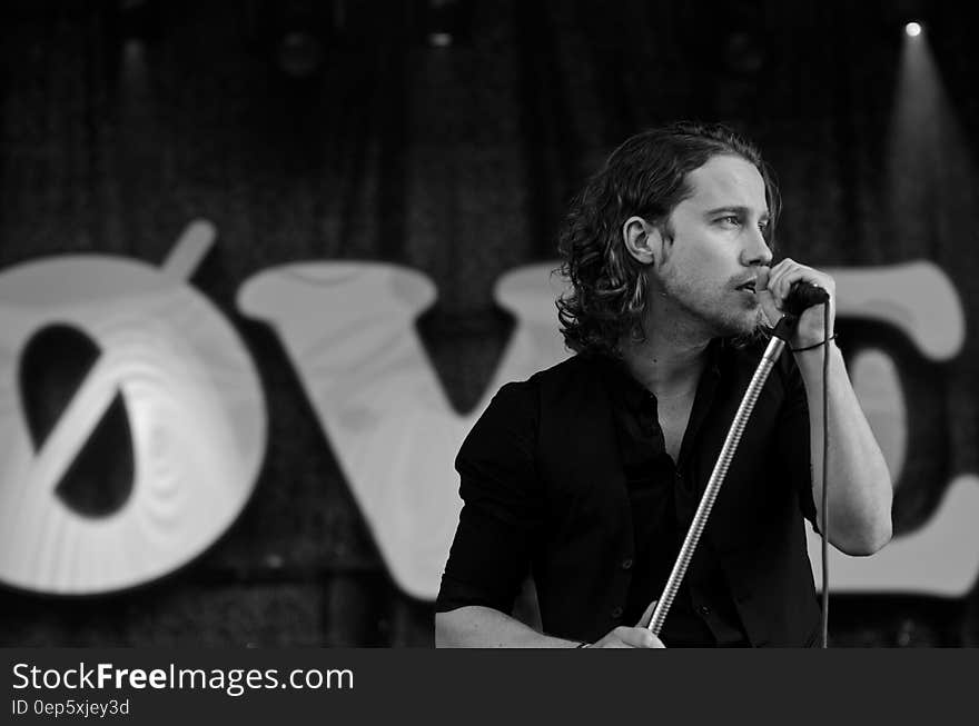 Grayscale Photography of Man Wearing Dress Shirt While Holding Microphone