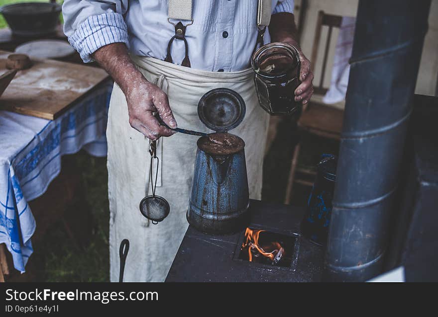 Man Holding Jar While Scooping on Kettle